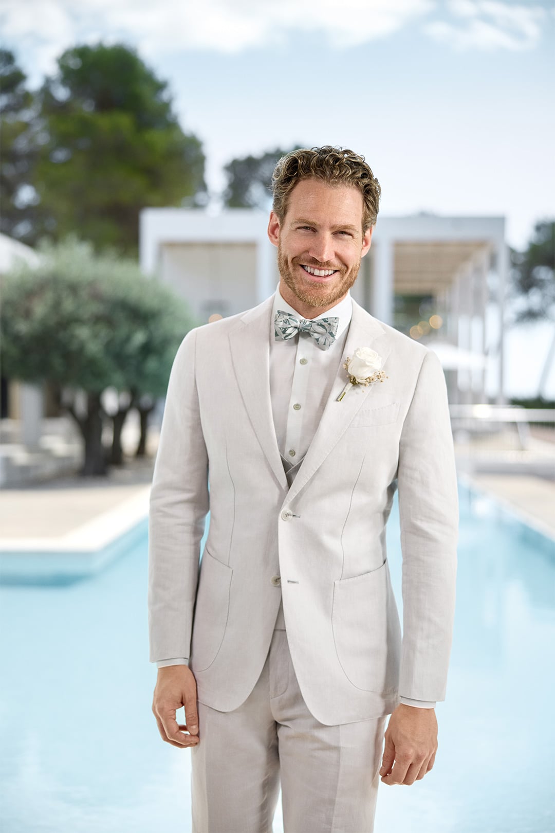 Modello indossa abito color crema con camicia OLYMP bianca.